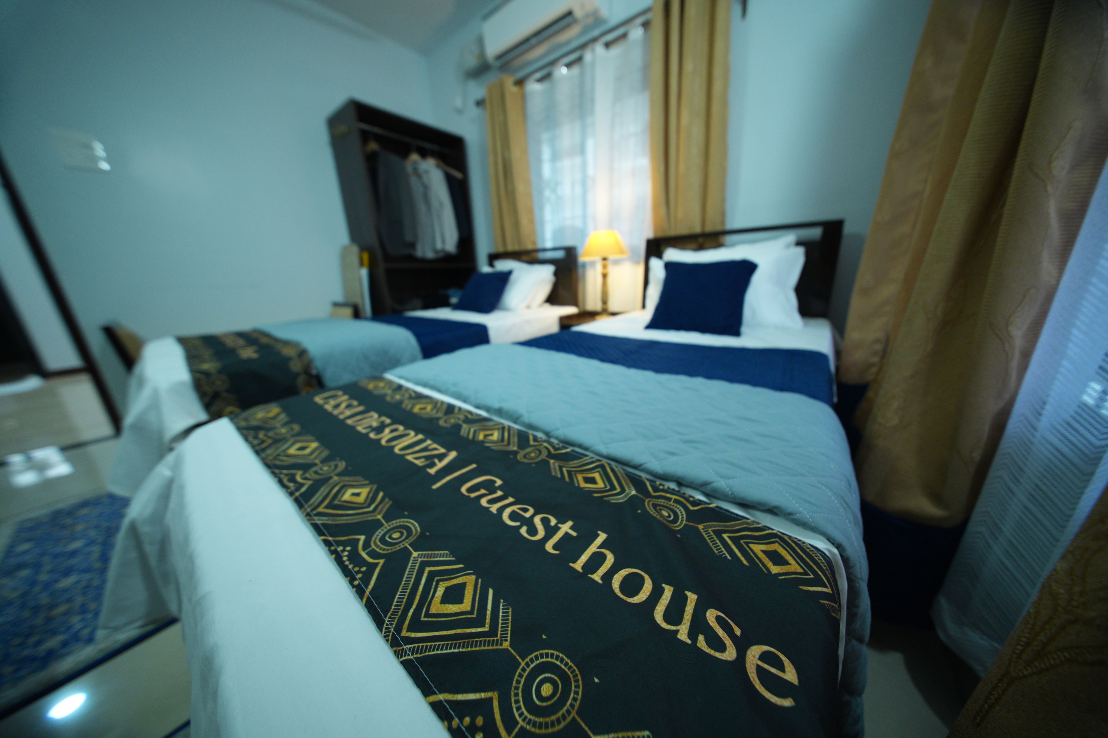 Habitación de hotel con dos camas, un armario y una ventana con cortinas.