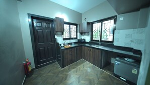 A kitchen with a herringbone floor pattern, wooden cabinets, a built-in oven, and a window with a view of greenery. - Casa de Souza (Verna)