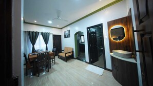 A living room with a dining area, a sofa, a ceiling fan, and a kitchen area with a sink and mirror. - Casa de Souza (Verna)
