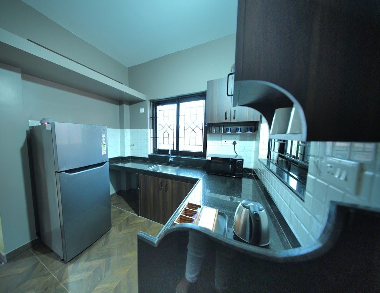Eine moderne Küche mit Kühlschrank, Mikrowelle, Spüle und Edelstahl-Schränken.