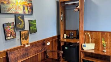 A room with a wooden bench, a wall-mounted mirror, a shelf with a handbag, and framed artwork.