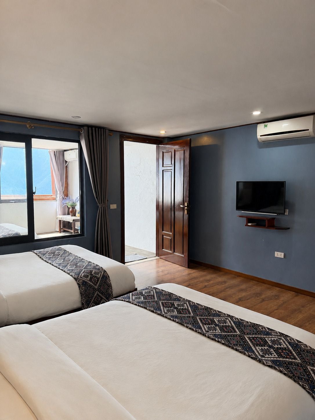 Een hotelkamer met twee bedden, een televisie en een airconditioner.