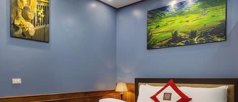 Una habitación de hotel con una cama bien hecha, una lámpara de pared y dos grandes cuadros de paisajes.