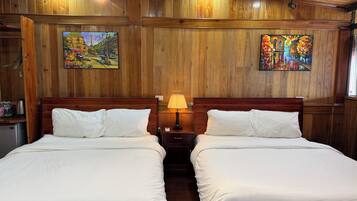 A room with two beds, wooden panel walls, and two paintings.