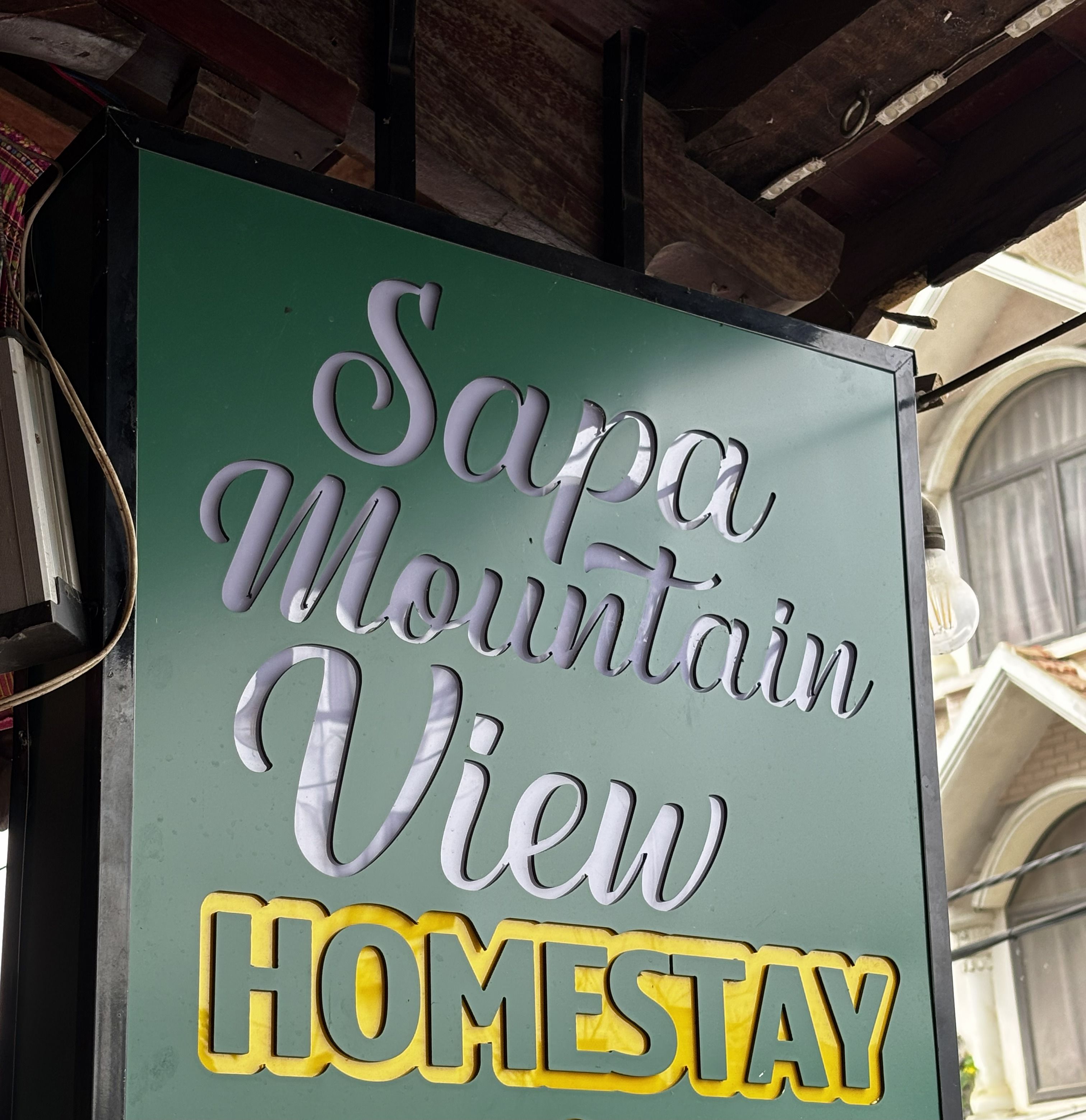 Schild mit 'Sapa Mountain View', wobei 'HOMESTAY' in Gelb hervorgehoben ist.