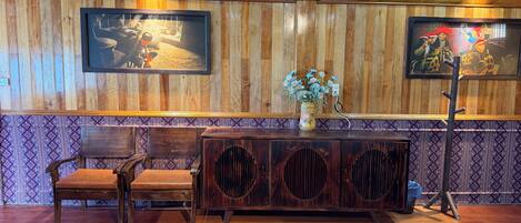 A room with wooden panel walls, a wooden bench, a cabinet with a floral vase, and two beds.