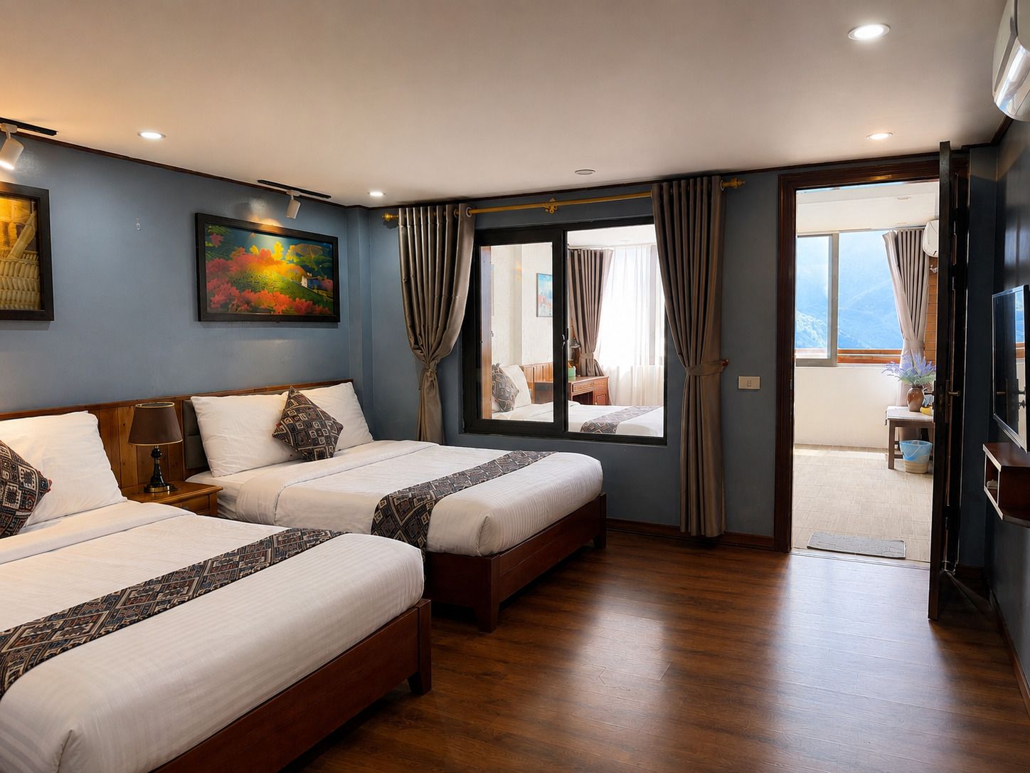 Una habitación de hotel con dos camas, un cuadro en la pared y vistas a través de la puerta.