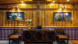 A wooden-paneled room with a desk, two chairs, a laptop, a vase with flowers, and two framed pictures on the wall. - Mountain View Homestay SaPa (Sa Pa)