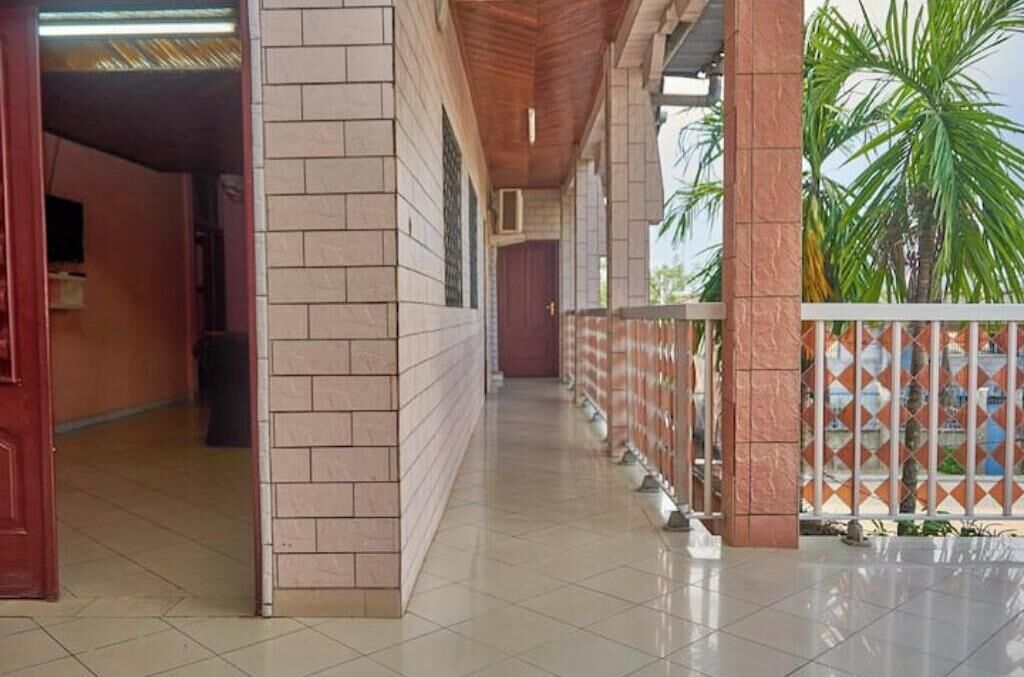 A corridor with tiled flooring, a wooden ceiling, and a brick wall.