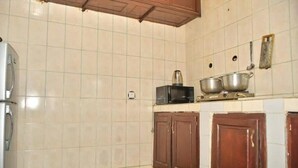 A kitchen with white tiled walls, a refrigerator, wooden cabinets, and a microwave. - NAL-Facing Apartment with Air Conditioning (Région du Littoral)
