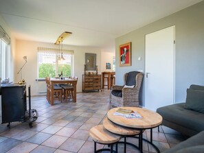 A spacious living area with a dining table, a wicker chair, a sofa, and a small wooden table. - Texel Getaway With Whirlpool (De Koog)
