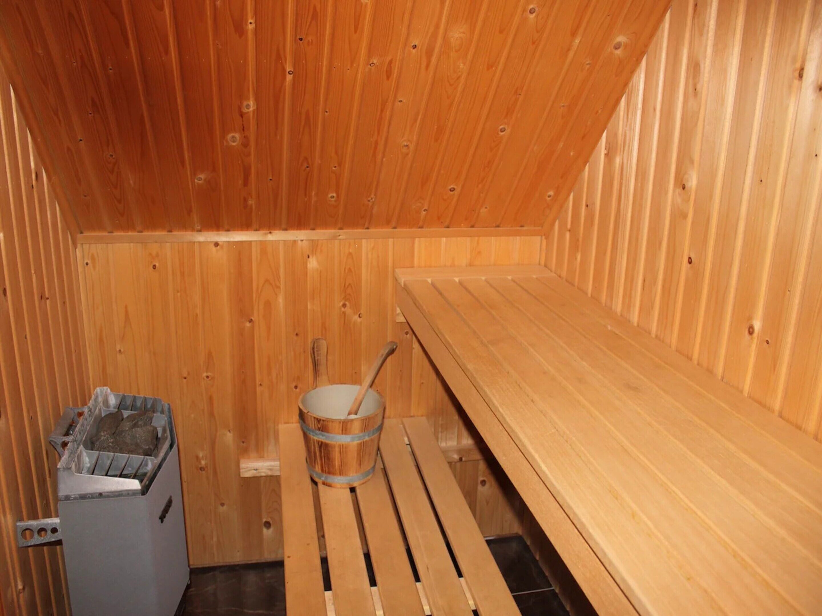Un sauna avec des bancs en bois et un seau.