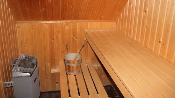 Sauna, jossa on puiset lauteet ja ämpäri.
