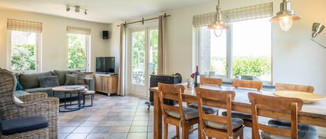 Un grand espace de vie comprenant une table à manger, des chaises, un canapé et un téléviseur.