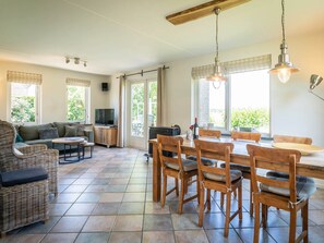 A spacious living area with a dining table, chairs, a sofa, and a television. - Texel Getaway With Whirlpool (De Koog)