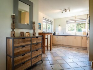 A kitchen with a large window, a wooden cabinet with drawers, and a tiled floor. - Texel Getaway With Whirlpool (De Koog)