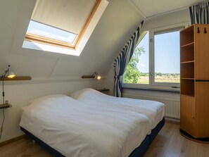 A bedroom with a skylight, a bed, a wardrobe, and a view of the outdoors. - Texel Getaway With Whirlpool (De Koog)