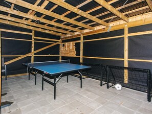 Une table de ping-pong dans une pièce dotée d’un plafond haut et de poutres apparentes.