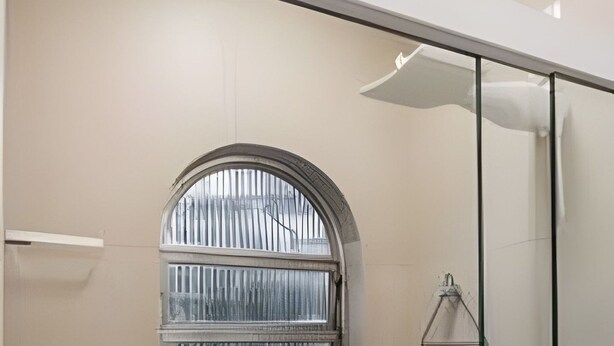 A bathroom with a glass shower enclosure, a small window with a metal grill, and a towel rack. - Aconchego Cotoxó - Loft 3 (São Paulo)