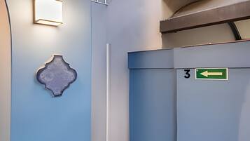 A hallway with a blue wall, a decorative piece, a door with a number sign, and an arrow sign.