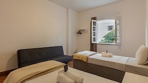 A hotel room with a bed, a sofa, a window with a view, and a ceiling fan. - Aconchego Cotoxó - Loft 3 (São Paulo)