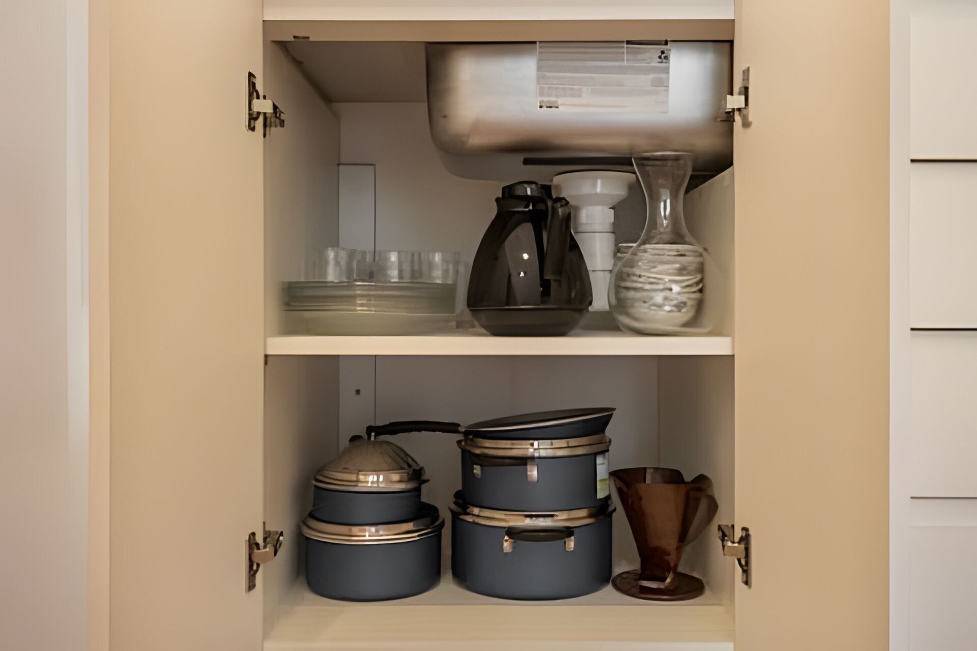 A kitchen cabinet with storage containers, a coffee maker, and a vase.