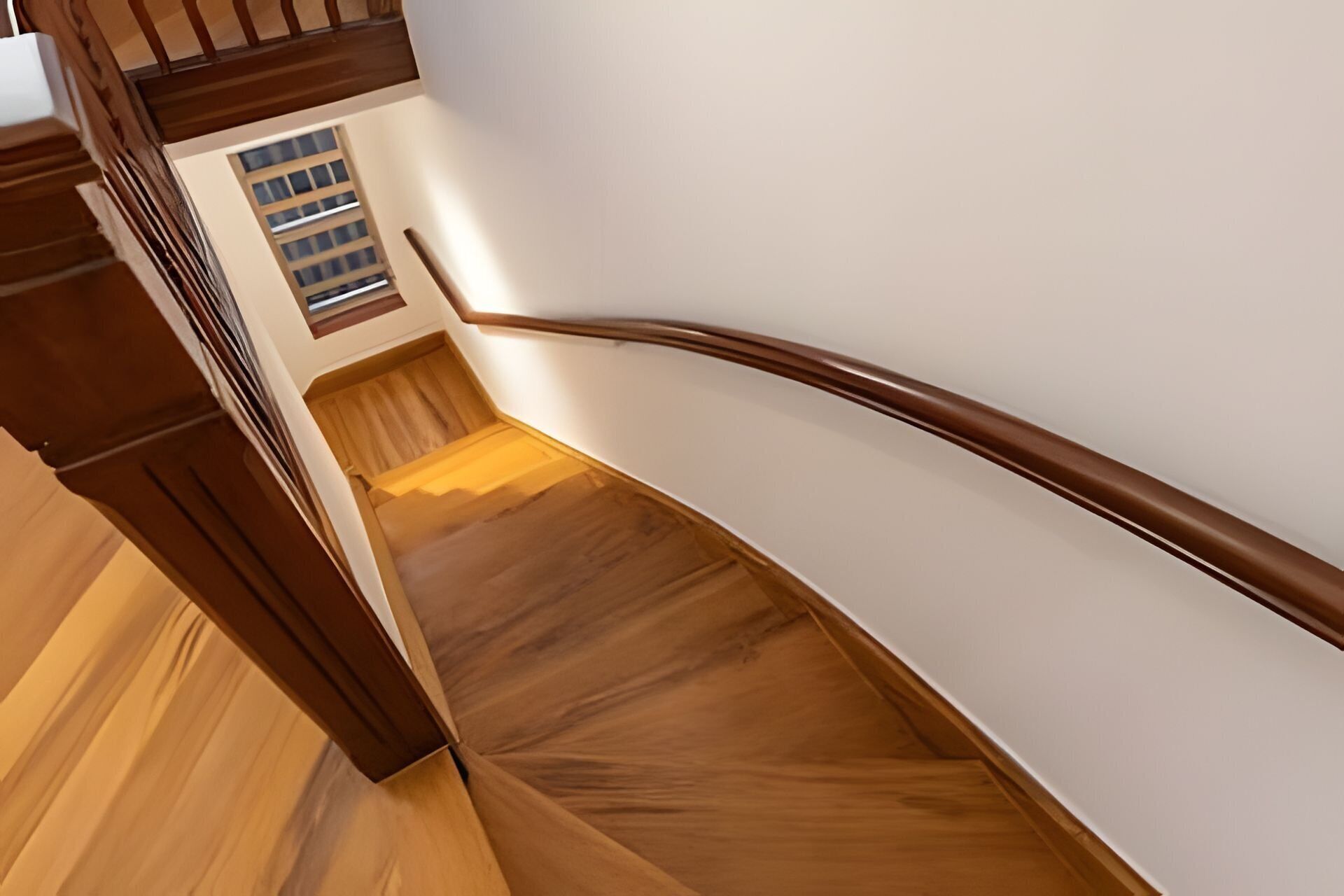 A wooden staircase with a handrail and a window at the top.