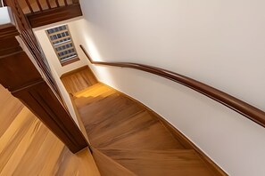 Eine Holztreppe mit Handlauf und einem Fenster am Obergeschoss.