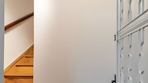 A staircase with wooden steps leading to a landing, a white wall, and a door with a glass panel design. - Aconchego Cotoxó - Loft 3 (São Paulo)