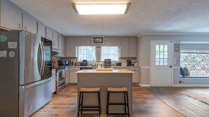 Una cucina moderna con isola centrale, elettrodomestici in acciaio inossidabile e vista sull'esterno.