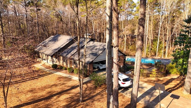 A cabin with a covered porch, a swimming pool, and a parked car.