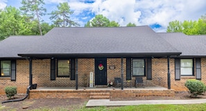 A two-story brick building with a porch, a welcome sign, and a black door.