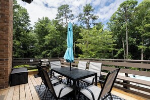 An outdoor patio with a table and chairs, a grill, and a pool in the background. - Mins to Truist Park & The Battery | Spacious East Cobb Home for Groups (Marietta)