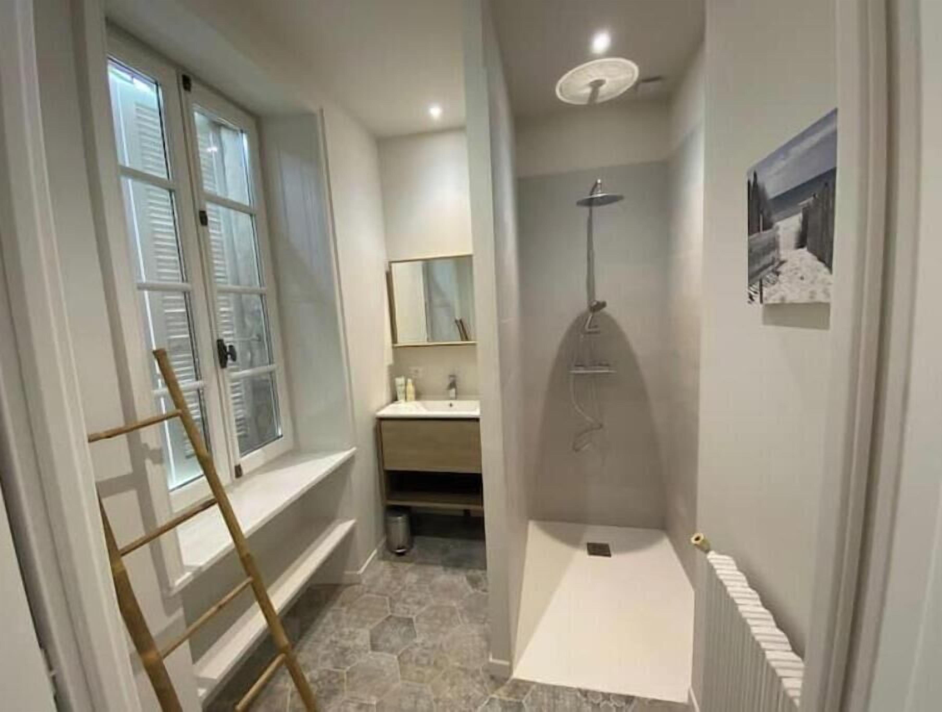 Un baño con ducha, ventana, espejo y radiador.