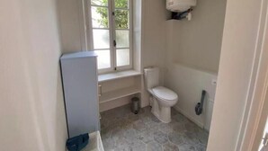 Een badkamer met toilet, raam en boiler.