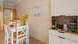 Uma cozinha moderna com cafeteira, mesa de jantar com cadeiras e arte decorativa na parede.