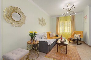 A living room with a sofa, a coffee table, a side table, a decorative mirror, a chandelier, and a patterned rug. - Apartment 'Magnolia' with Private Terrace, Wi-Fi and Air Conditioning (Tavira)