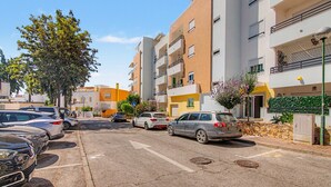 Uma rua residencial com carros estacionados, edifícios altos e céu claro.