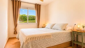 A bedroom with a bed, curtains, a nightstand with a lamp, and a window with a view. - Casa Valle Golf | Valle del Este Golf, Beach & Pool with garden in Vera (Vera)