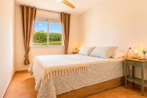 A bedroom with a bed, curtains, a nightstand with a lamp, and a window with a view. - Casa Valle Golf | Valle del Este Golf, Beach & Pool with garden in Vera (Vera)