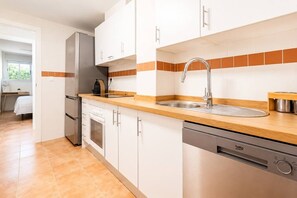 Eine moderne Küche mit weißen Schränken, einer Edelstahl-Spüle und einem Geschirrspüler.