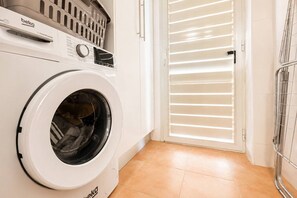 Eine Waschmaschine mit Frontlader, einer Bedieneinheit, einem Wäschekorb und einer Schiebetür zu einem Waschraum.