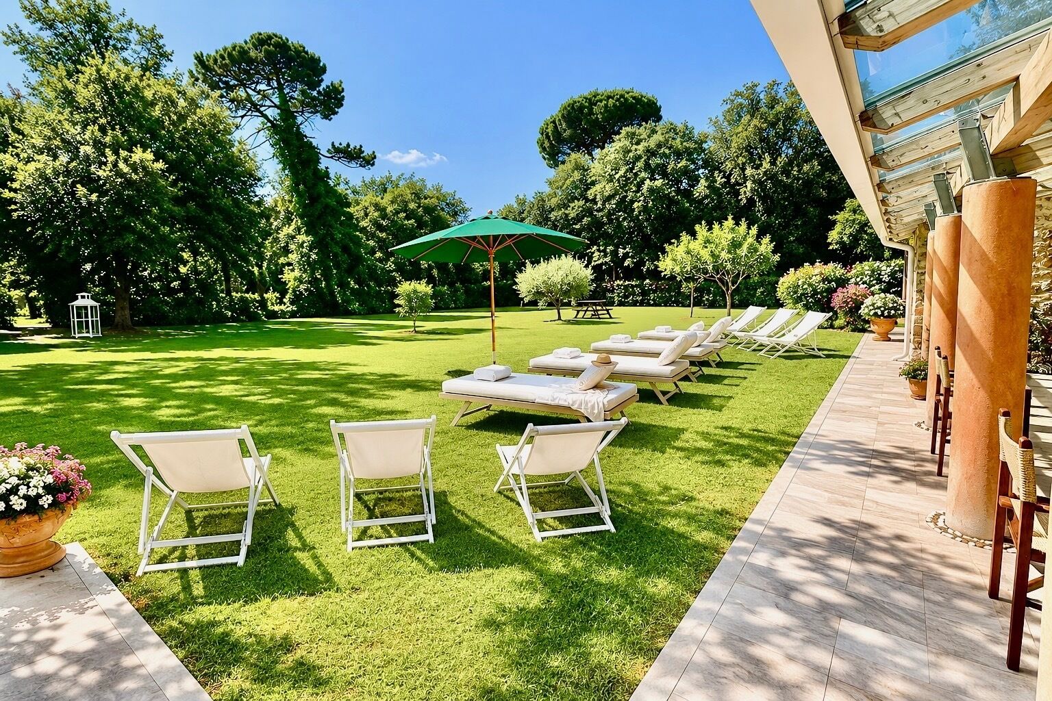 A patio with lounge chairs, a table, and a green umbrella.