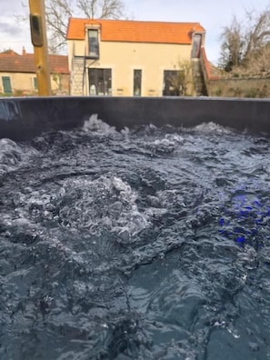 Een waterpartij met rimpelingen en een huis op de achtergrond.