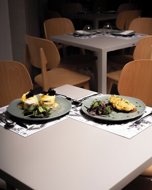 Una mesa de comedor con dos platos de comida, sillas alrededor y un menú.