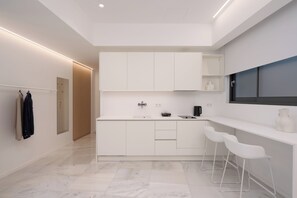 Una cocina moderna con armarios blancos, horno integrado y una ventana sobre la encimera.