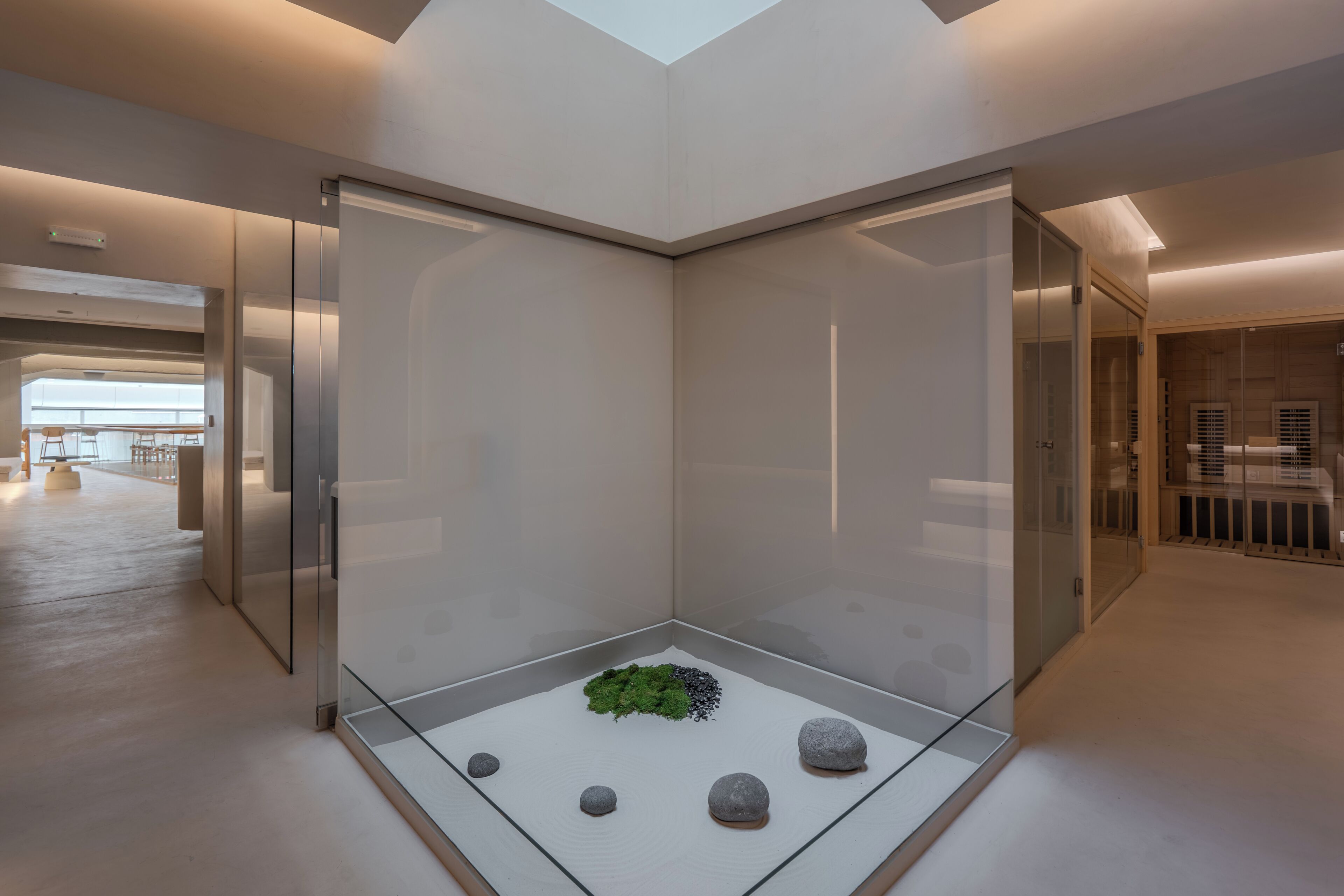 A modern interior with a glass partition, a minimalist design, and a small indoor garden.