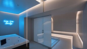 A modern bathroom with a glass shower enclosure, a neon sign reading 'ice ice baby,' and a bathtub with a control panel. - The George Athens (Athens)