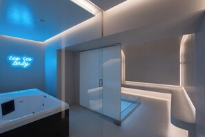 Un baño moderno con cabina de ducha de vidrio, un letrero de neón que dice 'ice ice baby' y una bañera con panel de control.