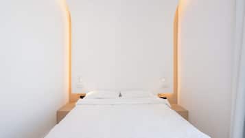 Habitación de hotel minimalista con una cama individual, dos mesitas de noche e iluminación en la pared.